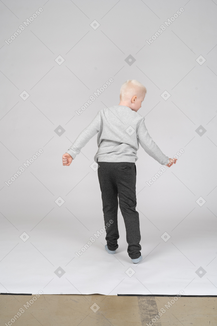Vista trasera de un niño con ropa informal dando vueltas