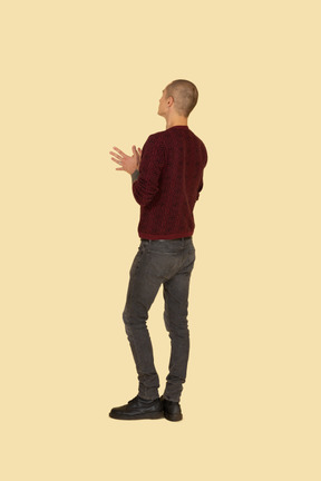 Three-quarter back view of an unknown gesticulating man in a red sweater
