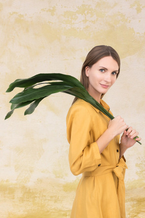 A woman in a yellow dress holding a green plant