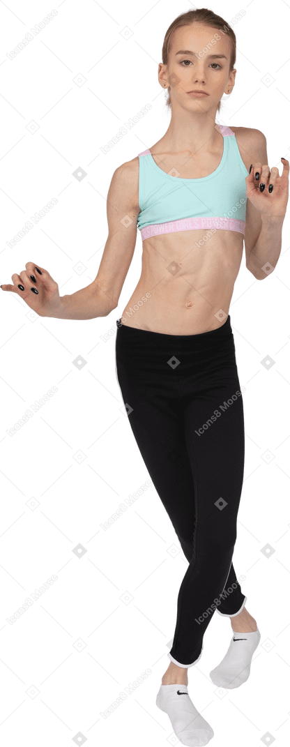 Vista frontal de uma adolescente em roupas esportivas cruzando as pernas e gesticulando enquanto dança