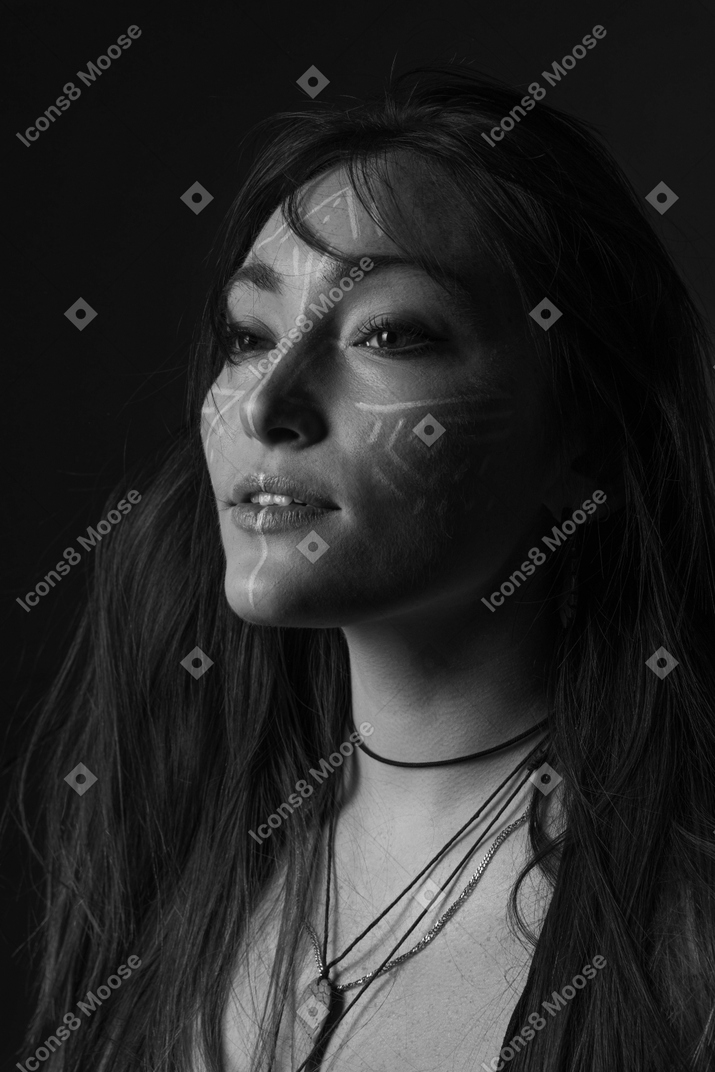 Side view noir picture of a young female with face art looking aside