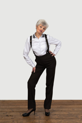 Front view of an old naughty female in office clothes bending down and grimacing putting hands on hips