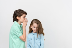 Boy whispering something in his sister's ear