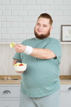 A fat man holding a bowl of salad