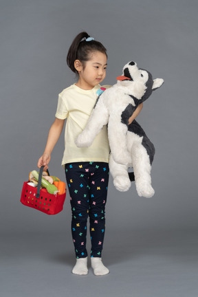 Portrait of a little girl holding a shopping basket and a dog plushie