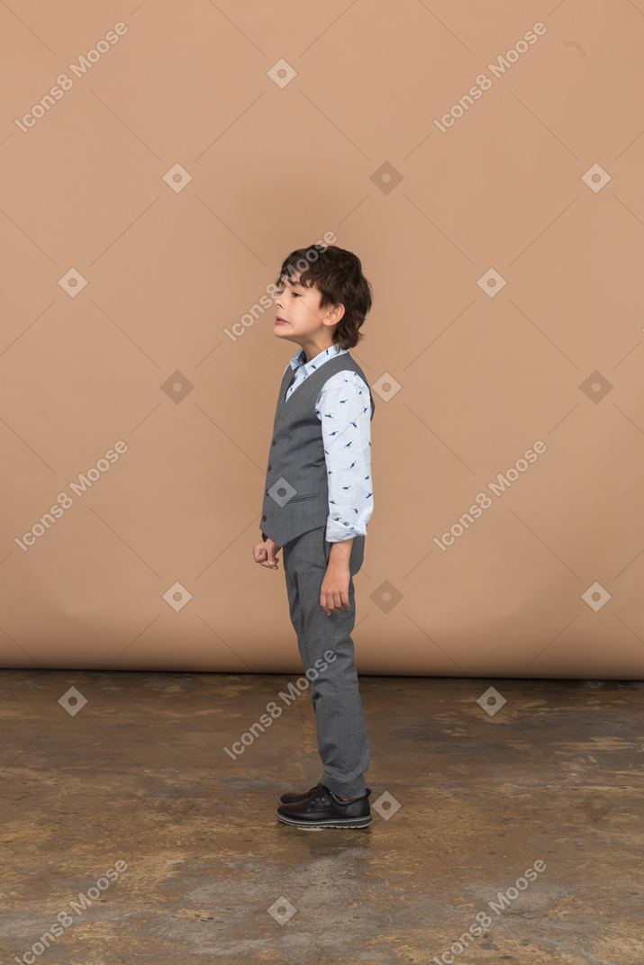 Cute boy in grey suit standing in profile