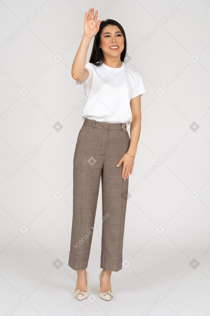 Front view of a greeting young woman in breeches raising her hand