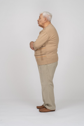 Side view of an old man in casual clothes blowing a kiss