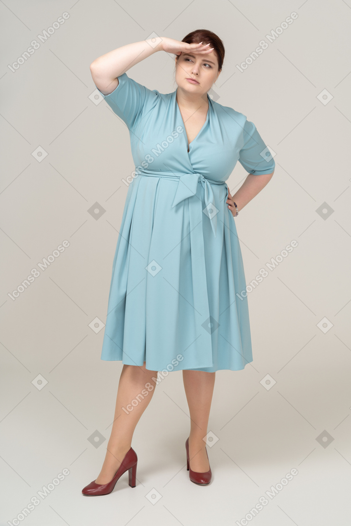 誰かを探している青いドレスを着た女性の正面図