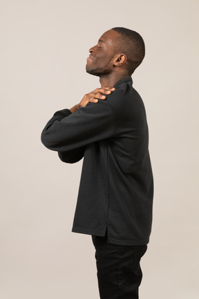 Side view of man embracing himself with eyes closed