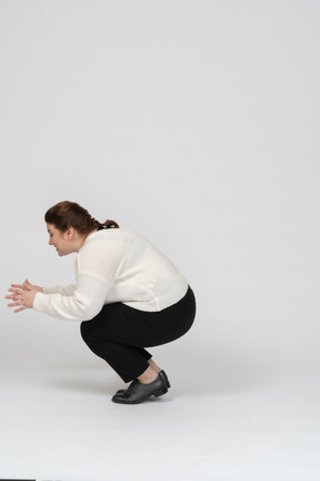 Side view of a plump woman in casual clothes squatting