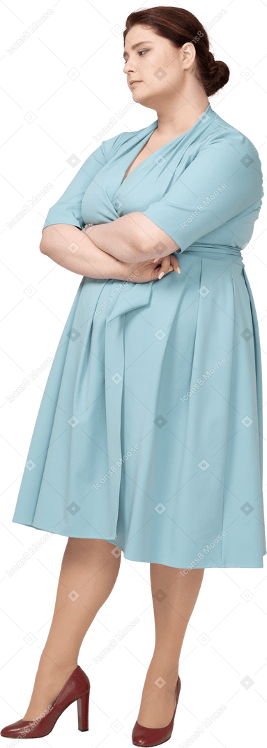 Vue de face d'une femme en robe bleue debout avec les bras croisés