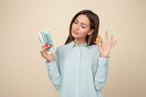 Attractive young woman holding a butcoin and dollar bills
