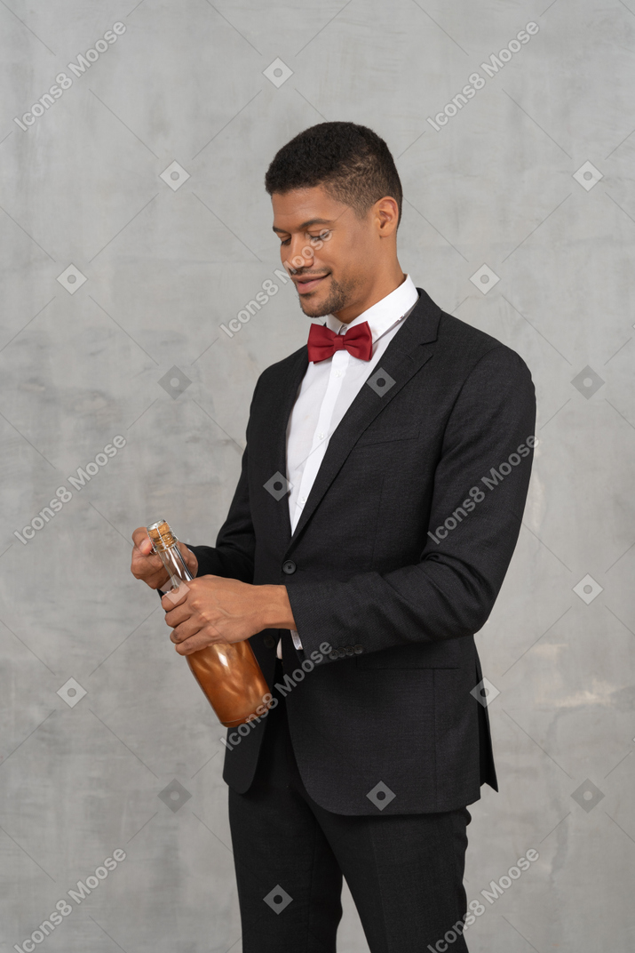 Gut gekleideter mann, der eine champagnerflasche öffnet