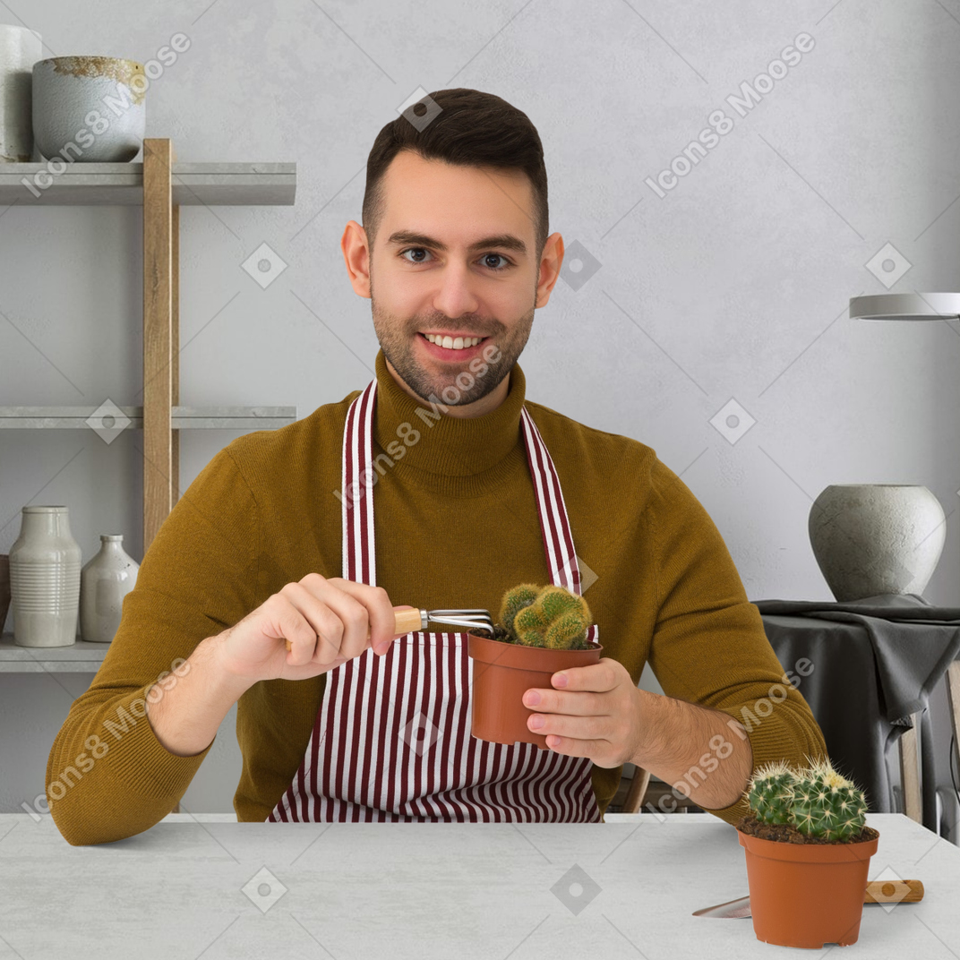 A man in an apron holding a potted plant