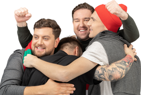 Close-up of four male football fans celebrating the victory & hugging