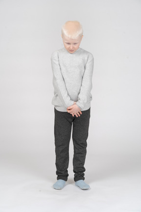 Front view of a sad ashamed kid boy looking down