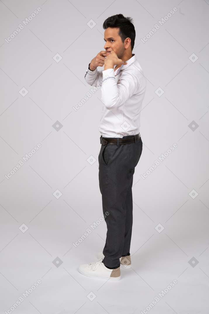 A man in a white shirt and black pants touching his face