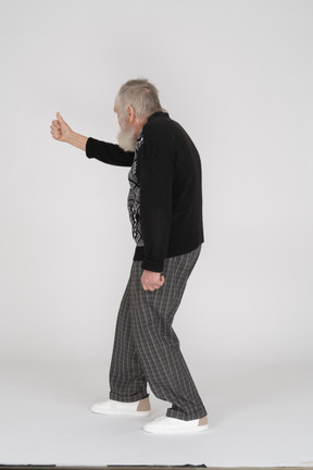 Rear view of old man giving thumbs up