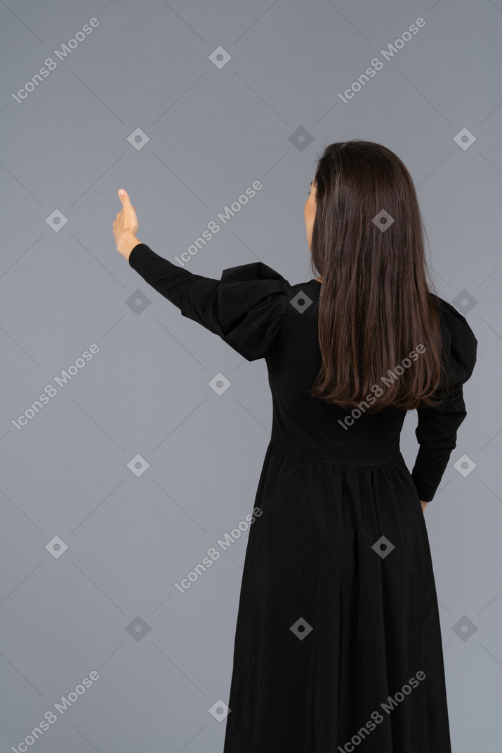 一位年轻的女士，穿着一件黑色的连衣裙，现身拇指的后视图