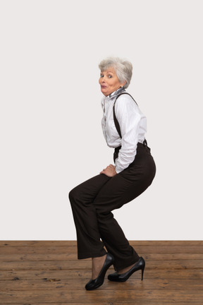 Side view of a woman in office clothes doing half squat