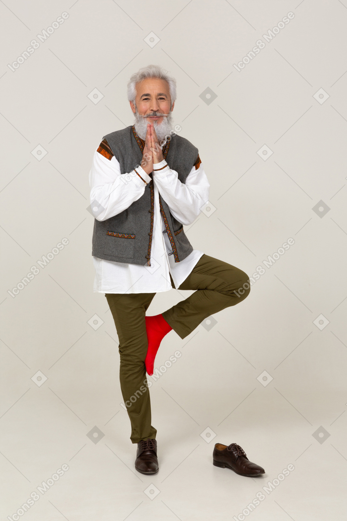 Uomo sorridente in piedi su una gamba con le mani giunte