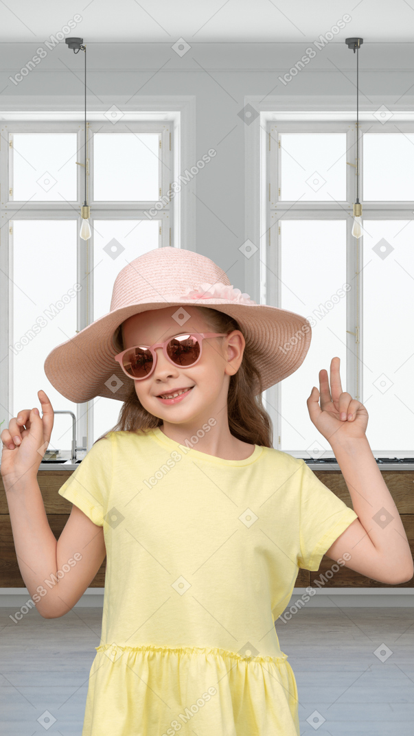 A girl wearing a hat and sunglasses stands in front of a window