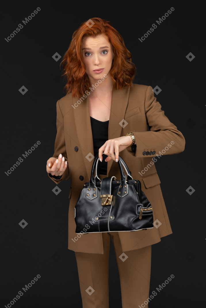 Young businesswoman holding up handbag