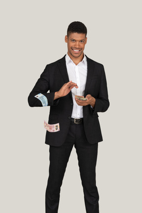 Front view of a young man in black suit wasting money