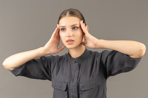 Vue de face d'une jeune femme en combinaison avec une peau propre touchant le visage