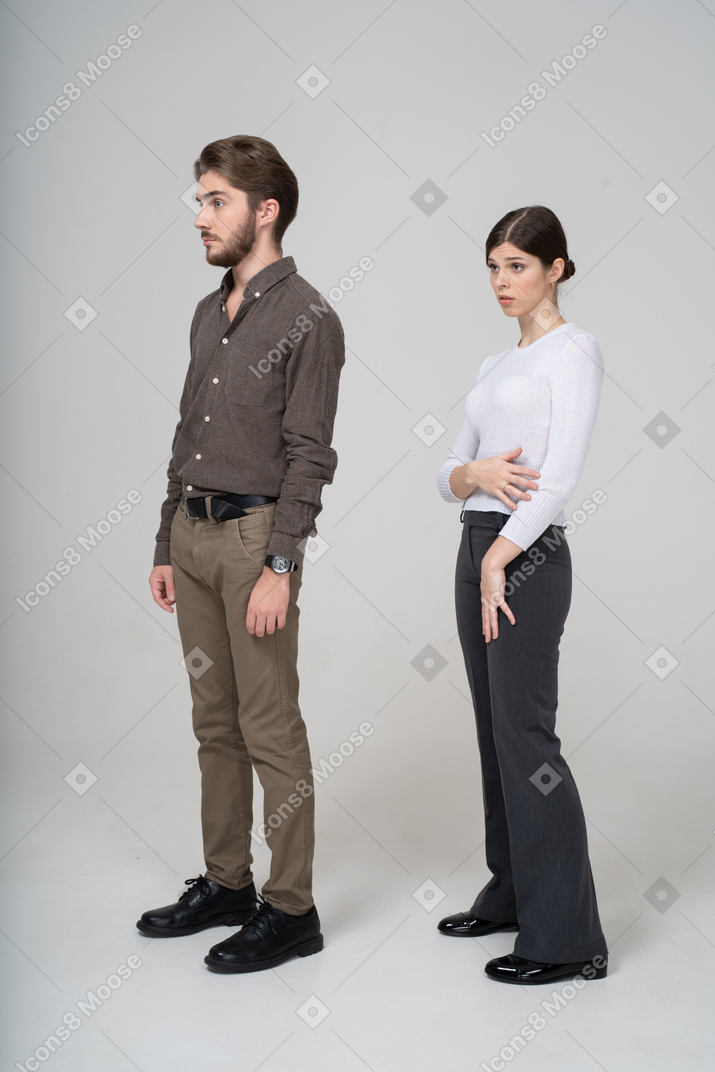Three-quarter view of a questioning young couple in office clothing