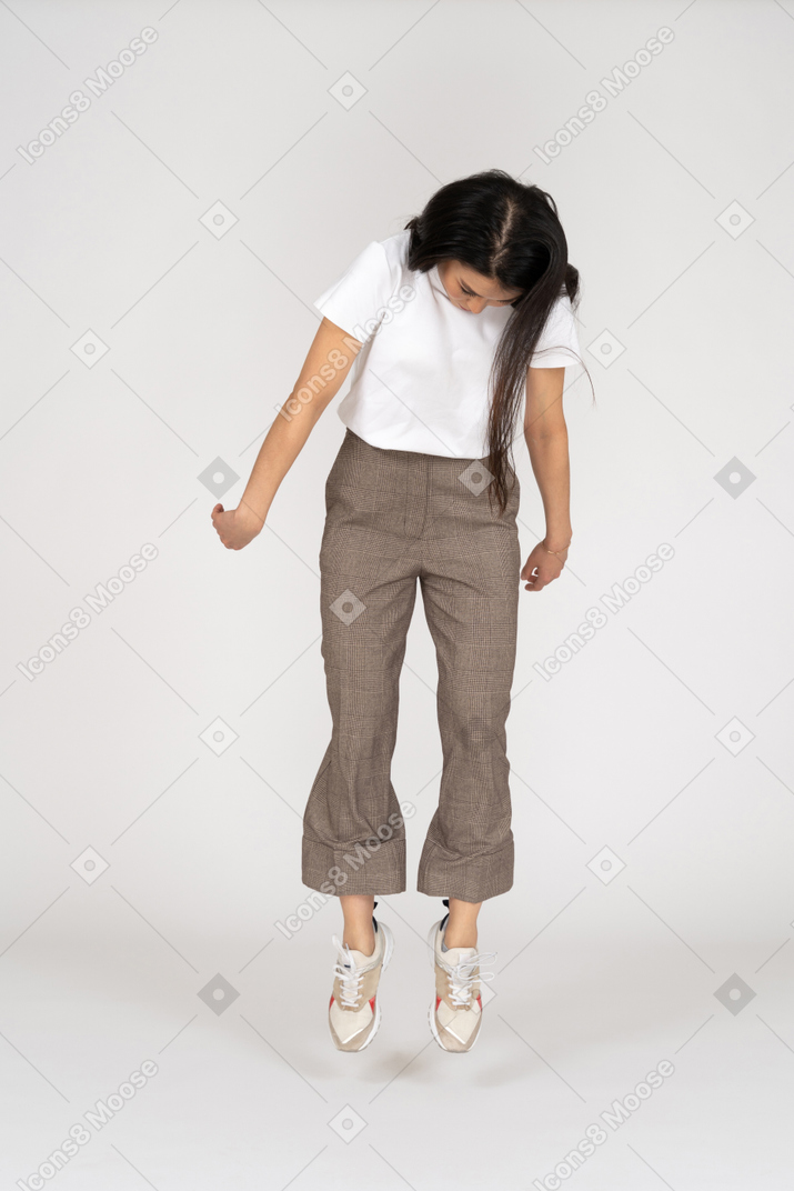 Front view of a jumping young lady in breeches and t-shirt looking down