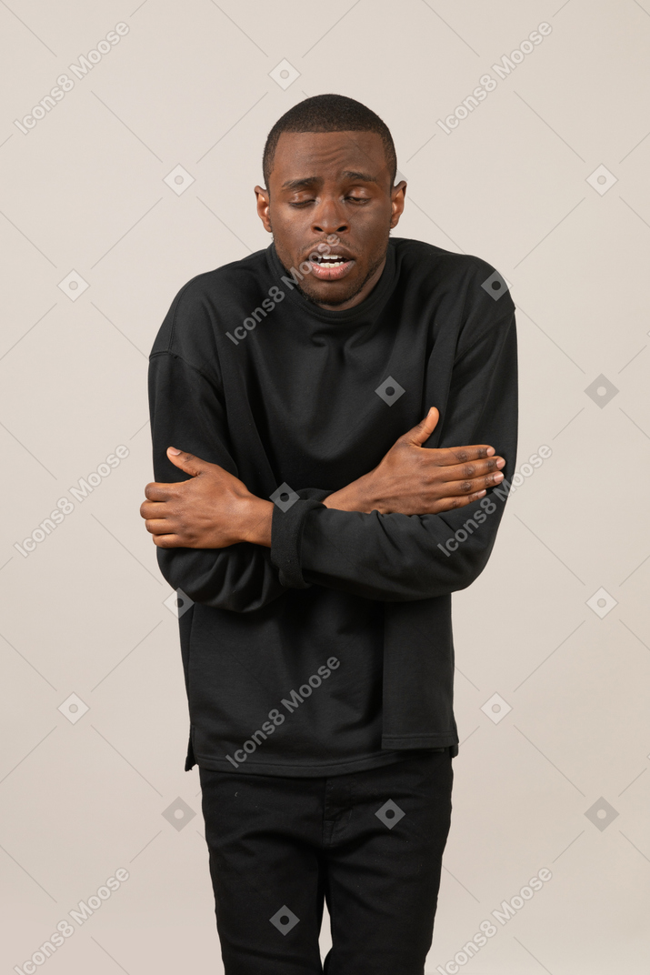 Front view of cold young man hugging himself