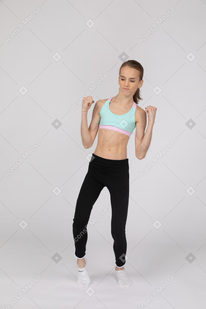 Девушка-подросток в спортивной одежде поднимает кулаки