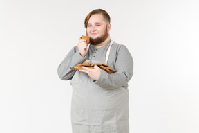 Um homem gordo segurando cookies e sorrindo