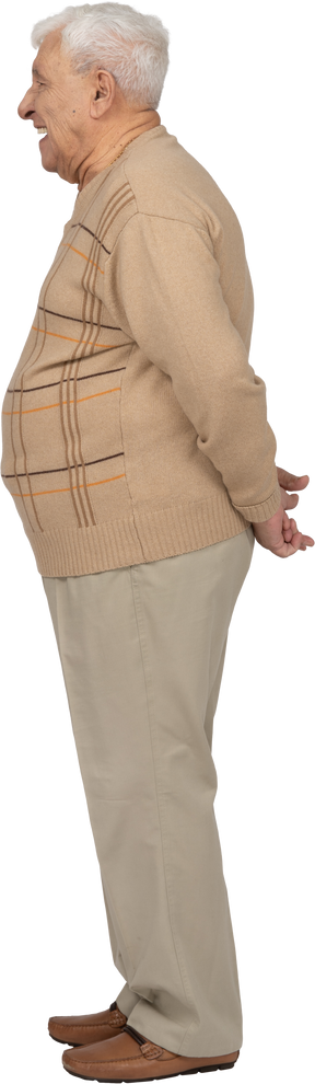 Vue latérale d'un vieil homme en vêtements décontractés debout avec les mains derrière le dos