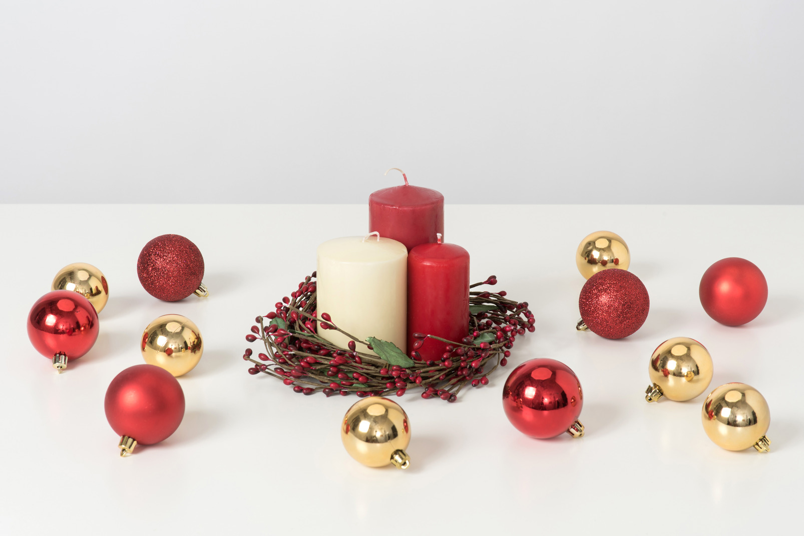 Three candles in minimalistic christmas wreath and decorations near it