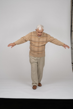 一位穿着休闲服的老人张开双臂向前走的正面图