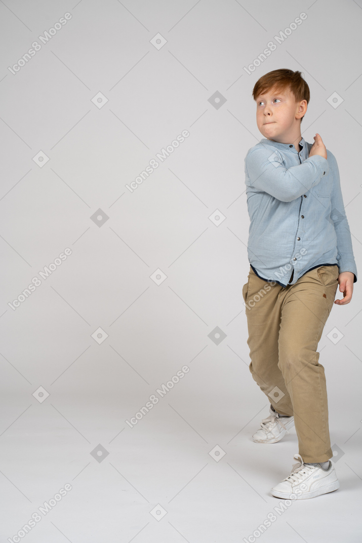 A young boy touching his shoulder