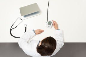 Uma médica olhando um esfigmomanômetro