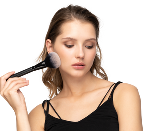 Vue de face d'une jeune femme sensuelle tenant un pinceau de maquillage
