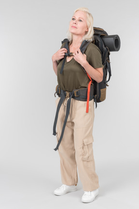 Mature female tourist standing in profile and carrying heavy backpack