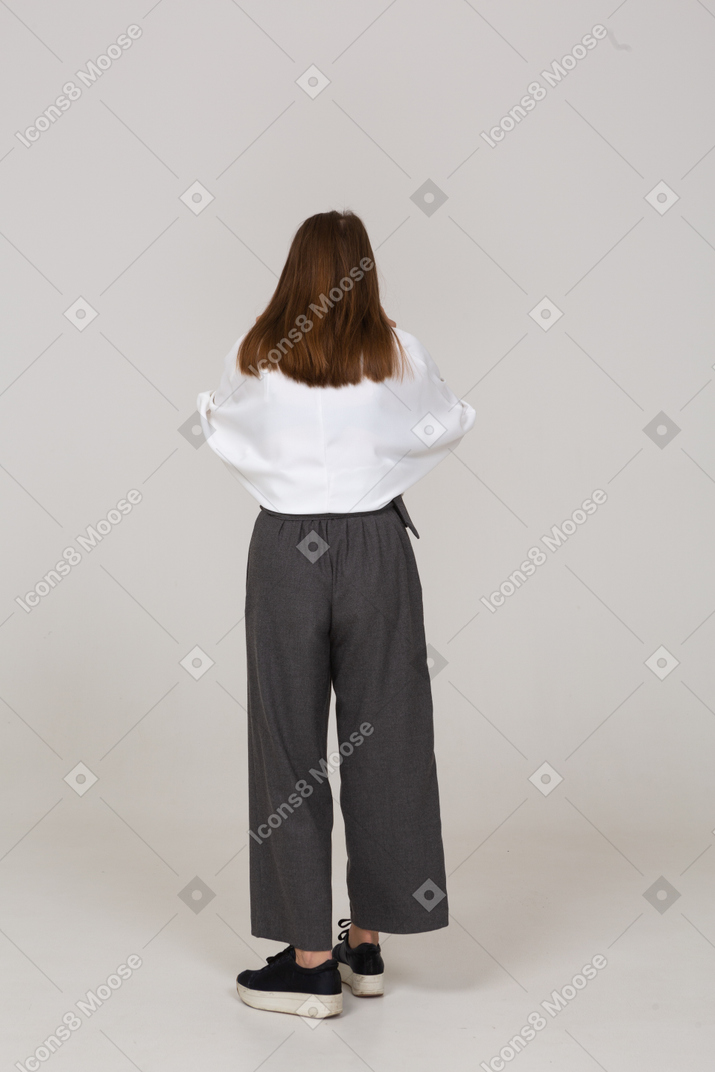 Vista posteriore di una giovane donna fischiettante in abiti da ufficio