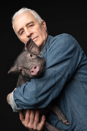 Miniature pig on elder man's hands