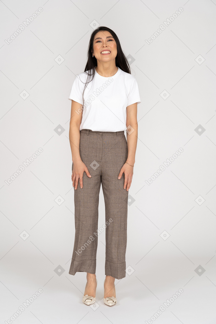 Vista frontal de uma jovem sorridente de calça e camiseta