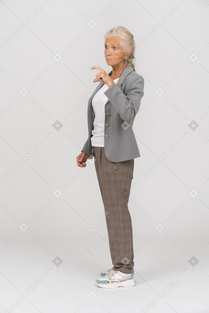 Vista laterale di una vecchia signora in abito che mostra una piccola dimensione di qualcosa