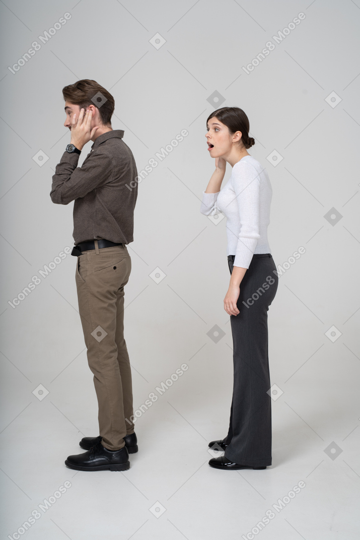 Side view of a young couple in office clothing listening to the rumors