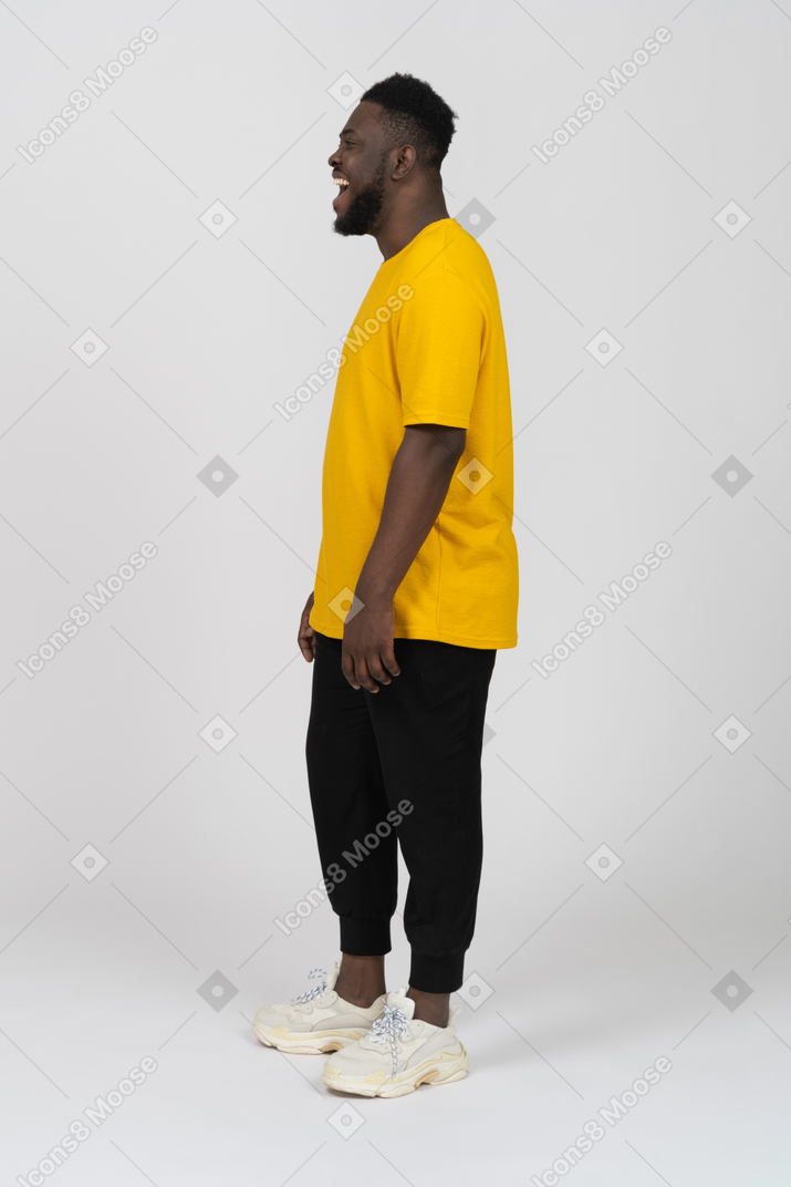 노란색 티셔츠를 입고 웃고 있는 검은 피부의 젊은 남자의 옆모습