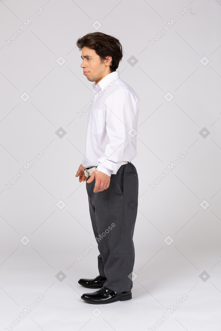 Vista lateral de um homem carrancudo em trajes formais olhando para longe