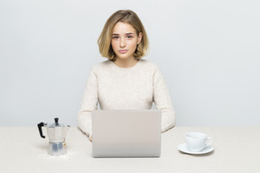 Garota atraente, trabalhando no laptop enquanto tomando café